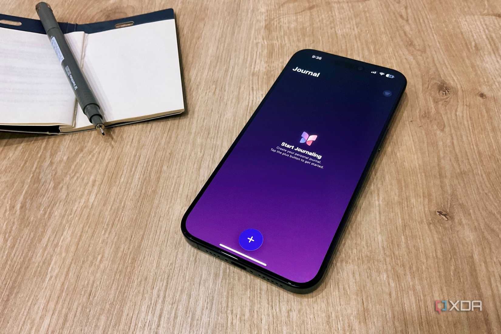 Apple Journal app on iPhone 15 Pro Max next to a notebook and pen