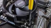 An image showing a CPU fan being screwed onto a motherboard.