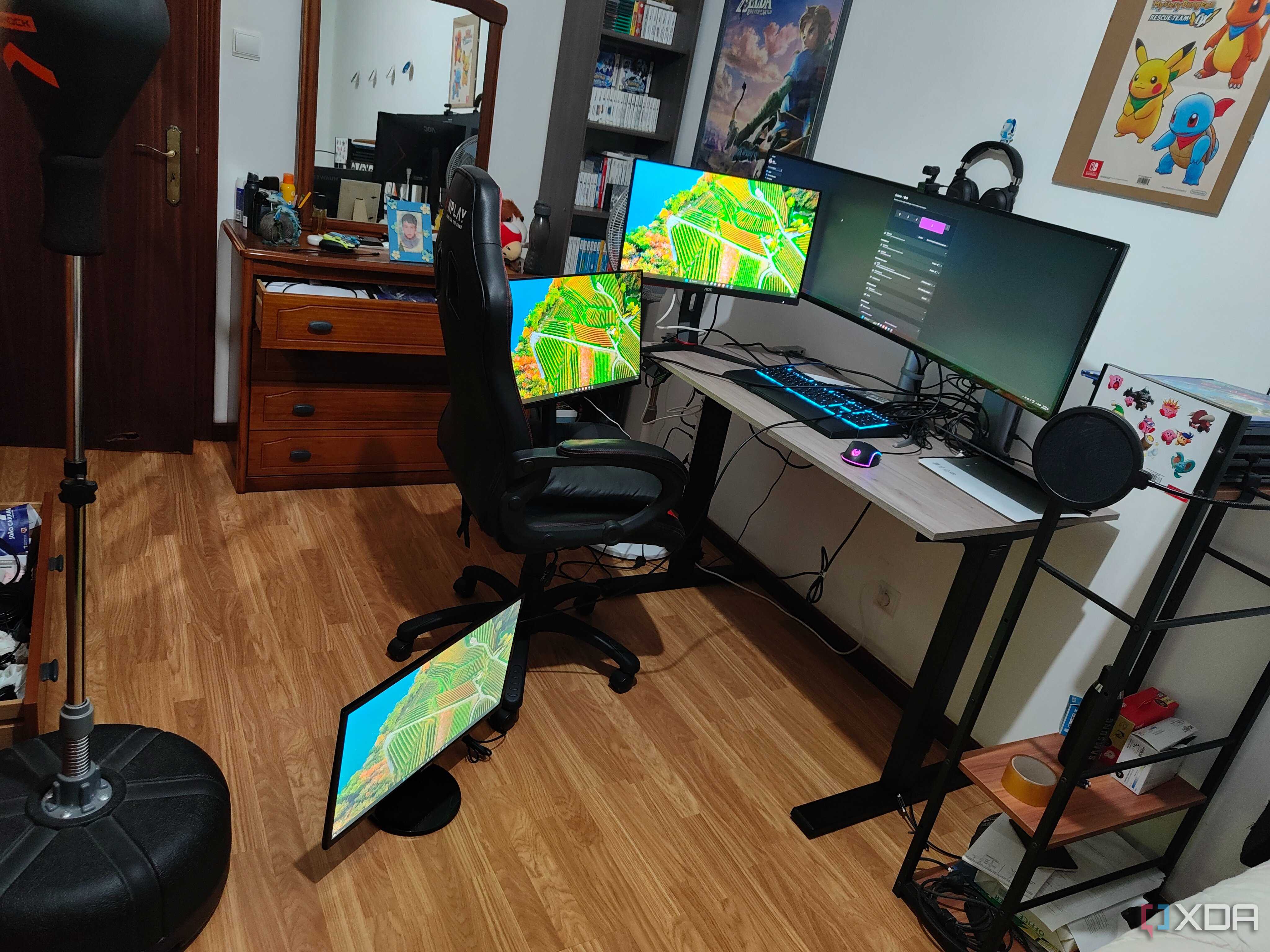 A computer desk with a laptop and four mopnitors on or arounds the desk, all connected to a dock, which is connected to a laptop. All the monitors are displaying the Windows 11 desktop