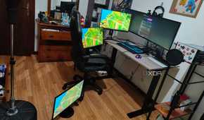 A computer desk with a laptop and four mopnitors on or arounds the desk, all connected to a dock, which is connected to a laptop. All the monitors are displaying the Windows 11 desktop