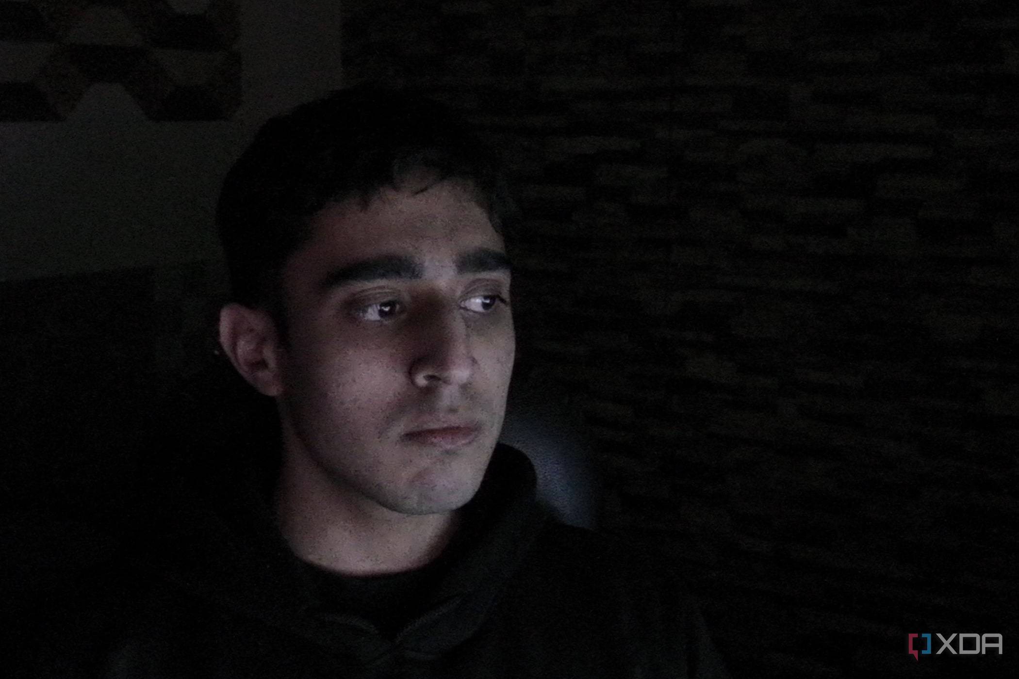 An image of a man sitting far away from the OBSBOT Tail Air webcam in a dark room