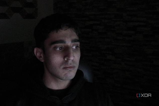 An image of a man sitting far away from the OBSBOT Tail Air webcam in a dark room