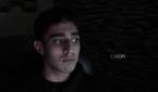 An image of a man sitting far away from the OBSBOT Tail Air webcam in a dark room