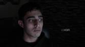 An image of a man sitting far away from the OBSBOT Tail Air webcam in a dark room