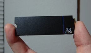 The Seagate Game Drive PS5 SSD held between two human fingers.