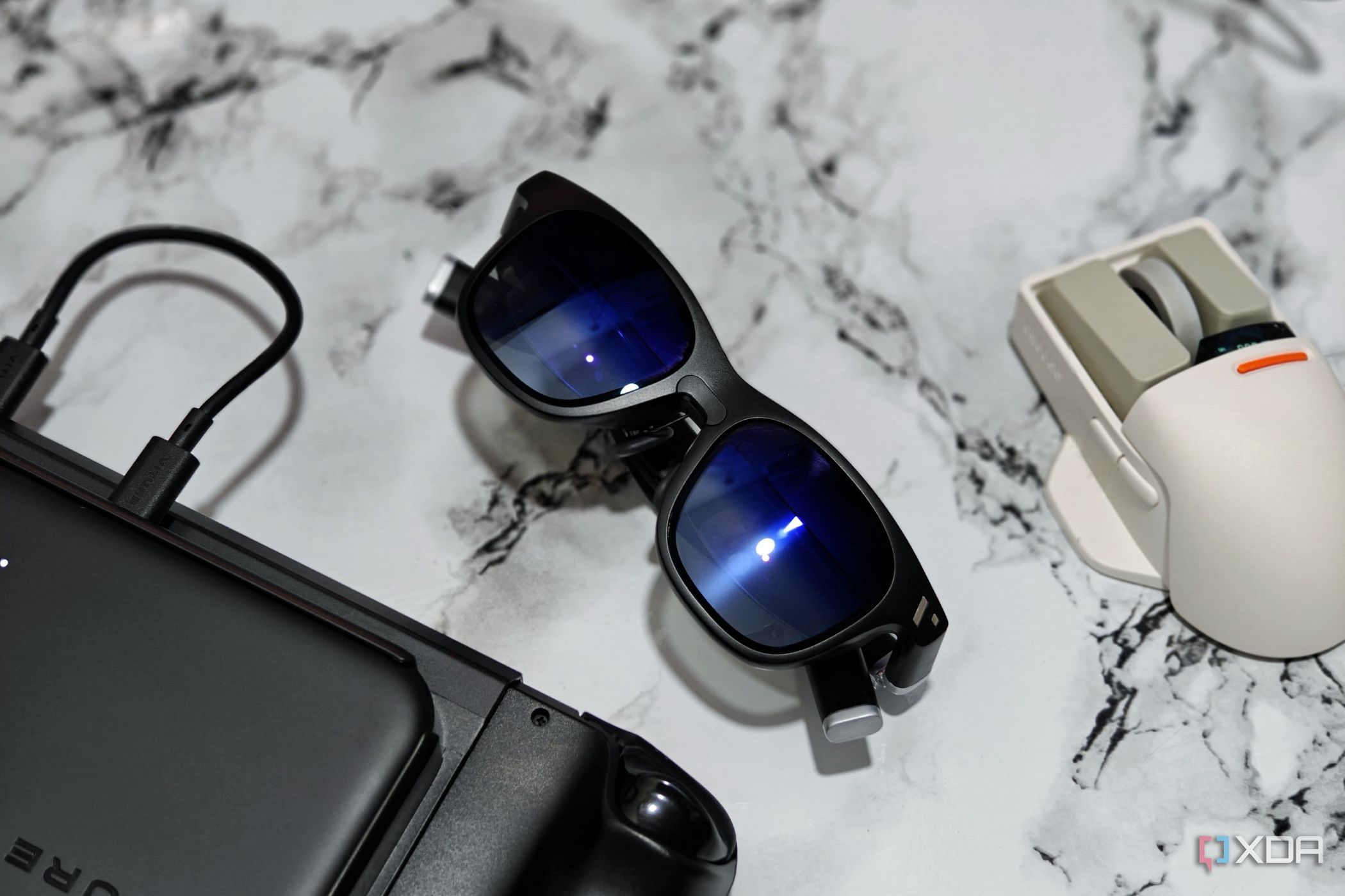 An image showing the Viture One glasses kept next to ta mouse and Steam Deck.