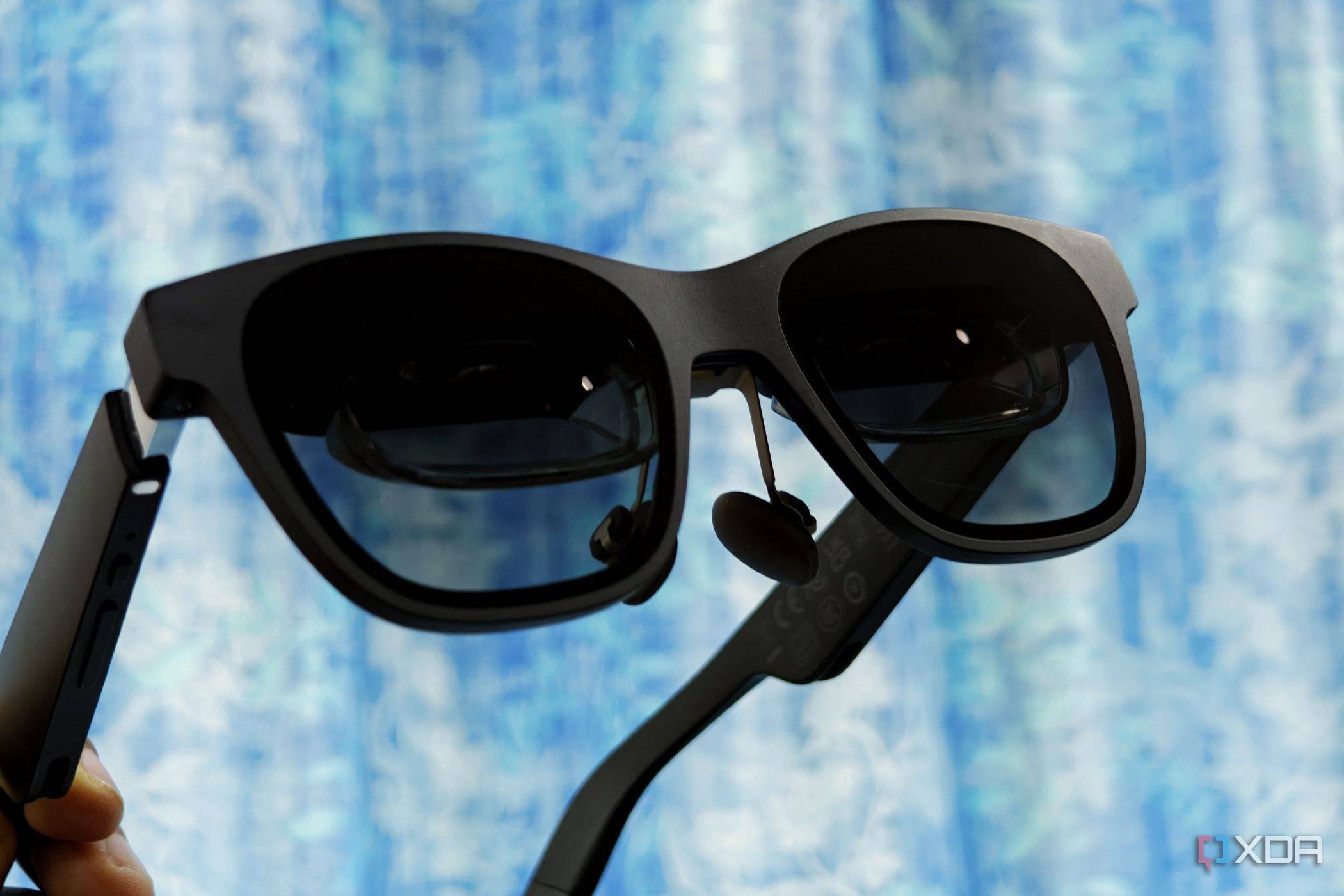 An image showing a person holding the XREAL Air 2 in their hand showing its front.