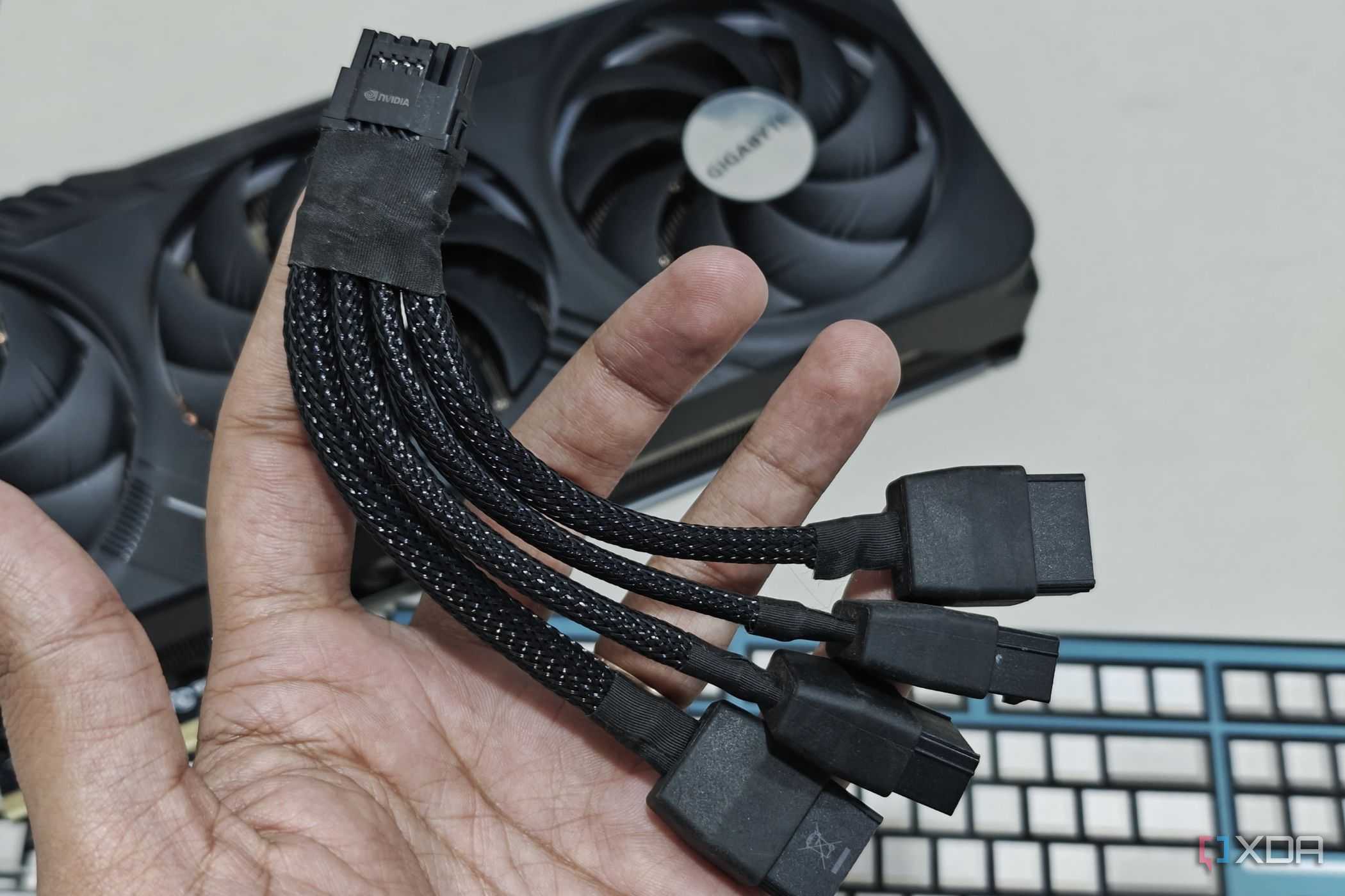 An image showing a person holding a 12VHPWR adapter cable in hand with the Gigabyte GeForce RTX 4070 Ti Gaming OC GPU in the background.