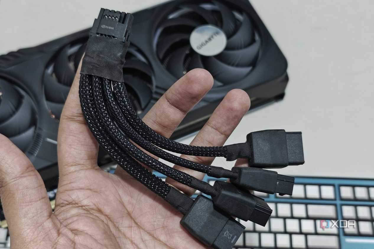 An image showing a person holding a 12VHPWR adapter cable in hand with the Gigabyte GeForce RTX 4070 Ti Gaming OC GPU in the background.
