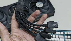 An image showing a person holding a 12VHPWR adapter cable in hand with the Gigabyte GeForce RTX 4070 Ti Gaming OC GPU in the background.