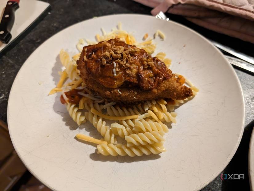 Chicken Parmigiana on top of pasta with tomato sauce