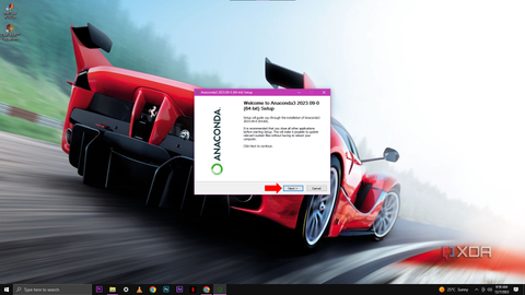 A screenshot of the initial setup window for Anaconda3 2023.09 (64-bit), with a red arrow pointing to the "Next" button, overlaid on a desktop background featuring a red sports car in motion.