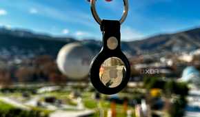 floating Apple AirTag keychain with greenery in the background