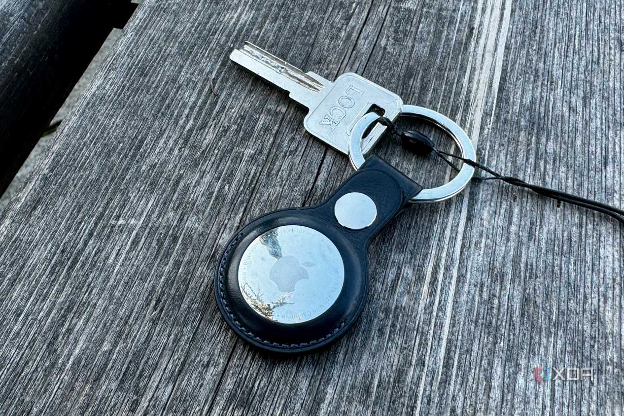 Apple AirTag keychain with a key placed on a wooden bench