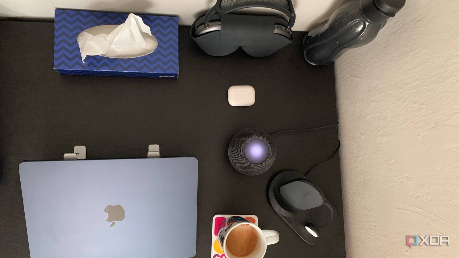 HomePod Mini, MacBook Air M2, AirPods Max, AirPods Pro, and Belkin wireless charger placed on a black table