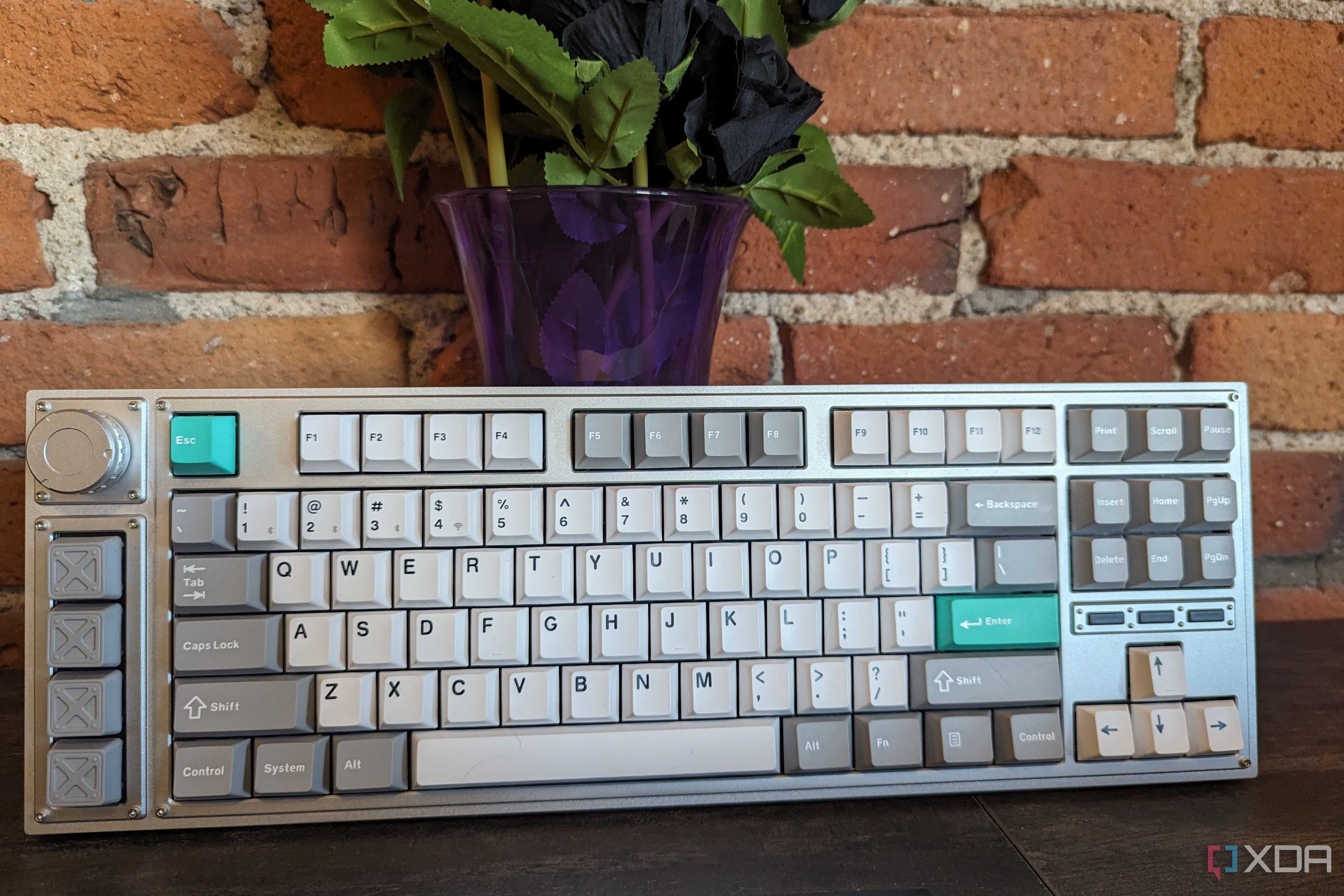A Lemokey L3 stood up in front of a brick wall and a vase