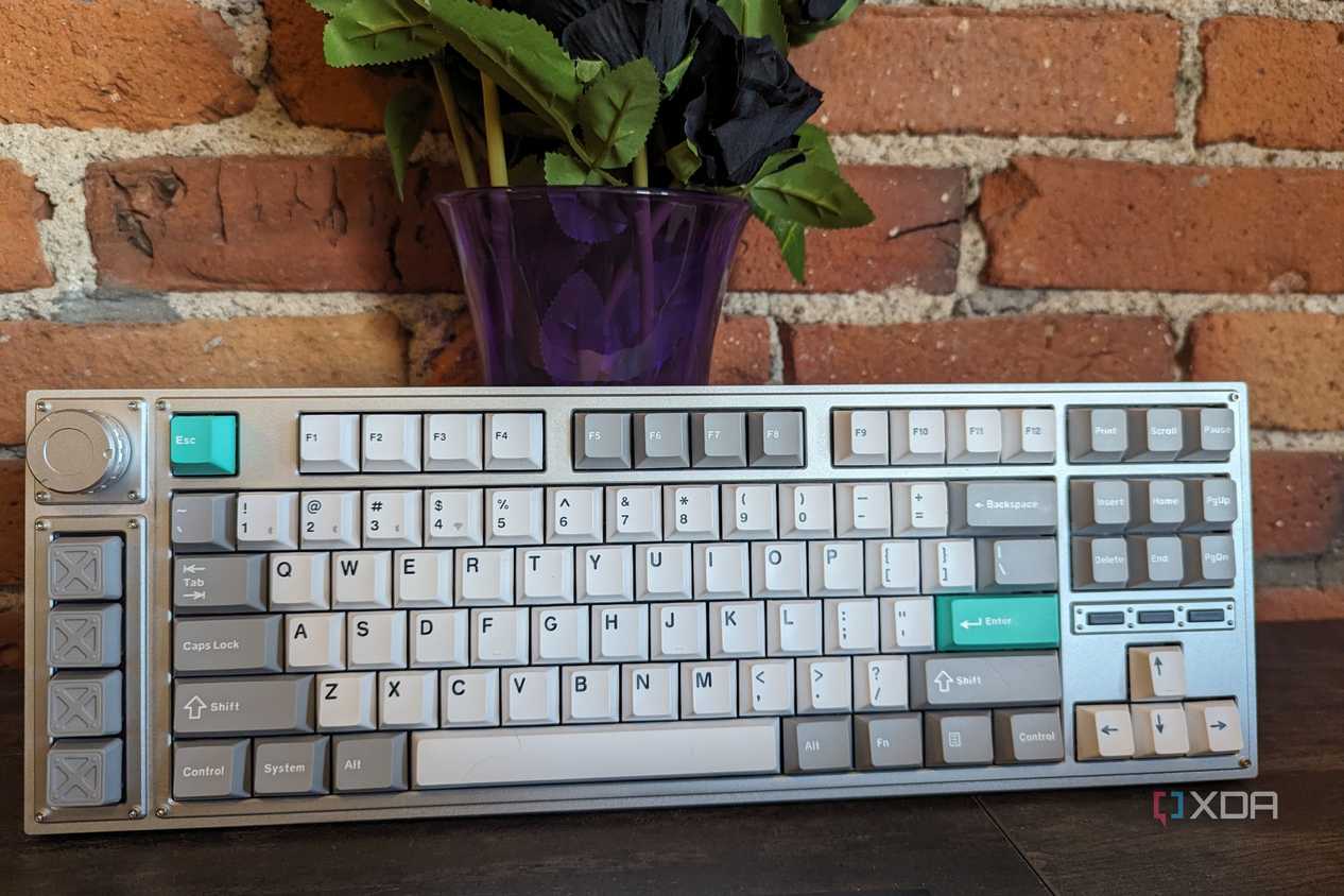 A Lemokey L3 stood up in front of a brick wall and a vase
