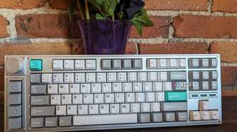 A Lemokey L3 stood up in front of a brick wall and a vase