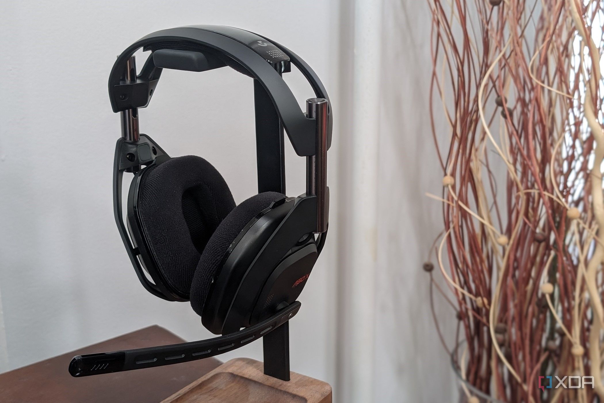 A photo of the Logitech G Astro 50 X Lightspeed sitting on a holder with a plant in the background