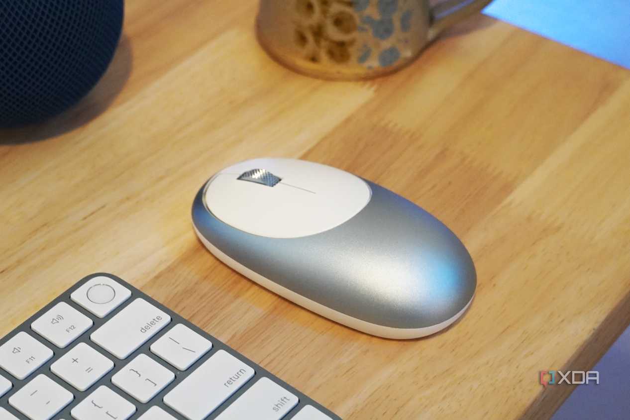 A blue M1 mouse on a desk with a keyboard.