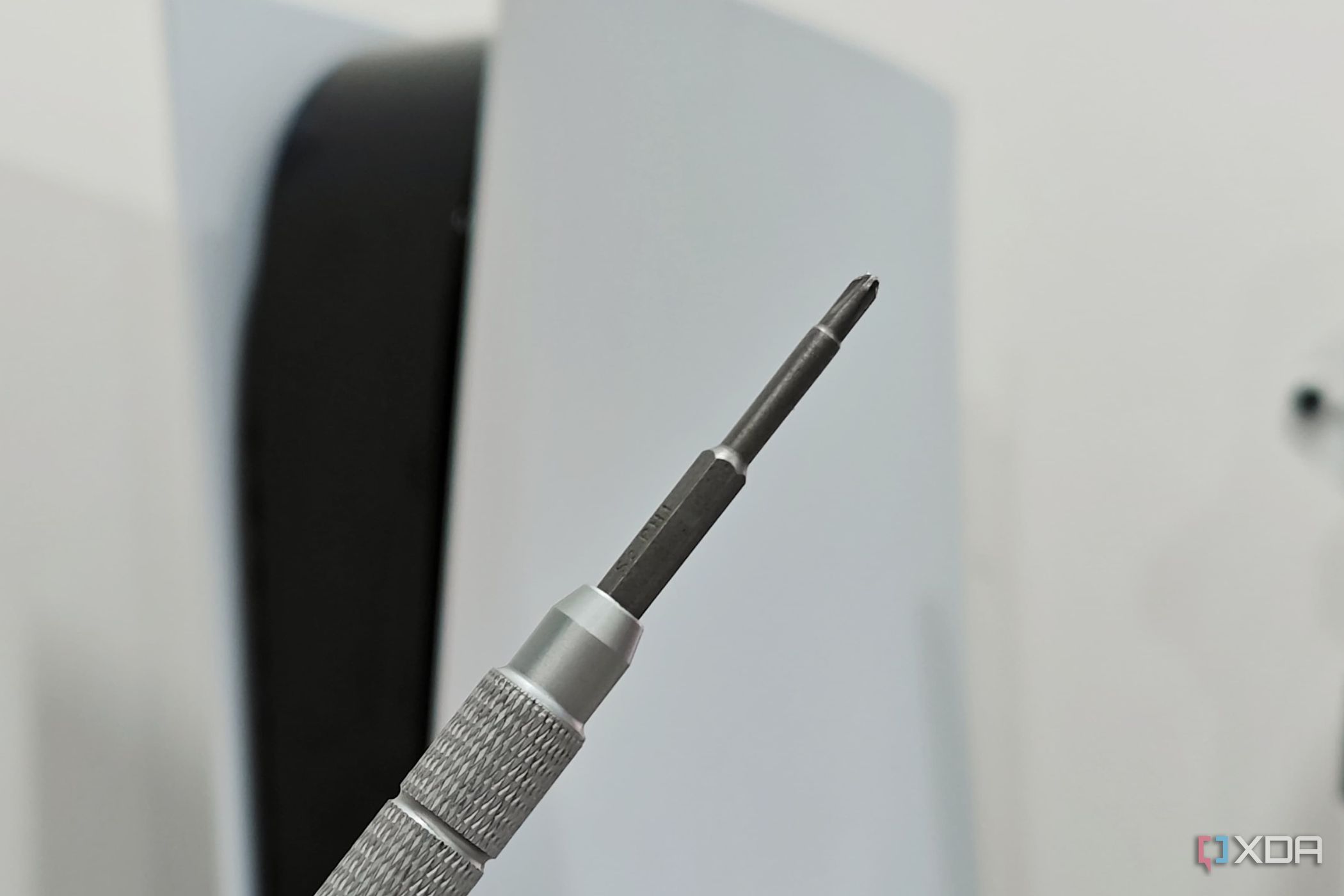 An image showing a Philips head screwdriver with a PS5 in the background.