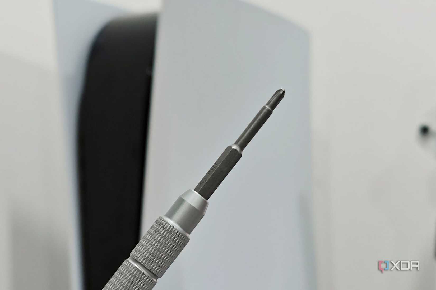 An image showing a Philips head screwdriver with a PS5 in the background.
