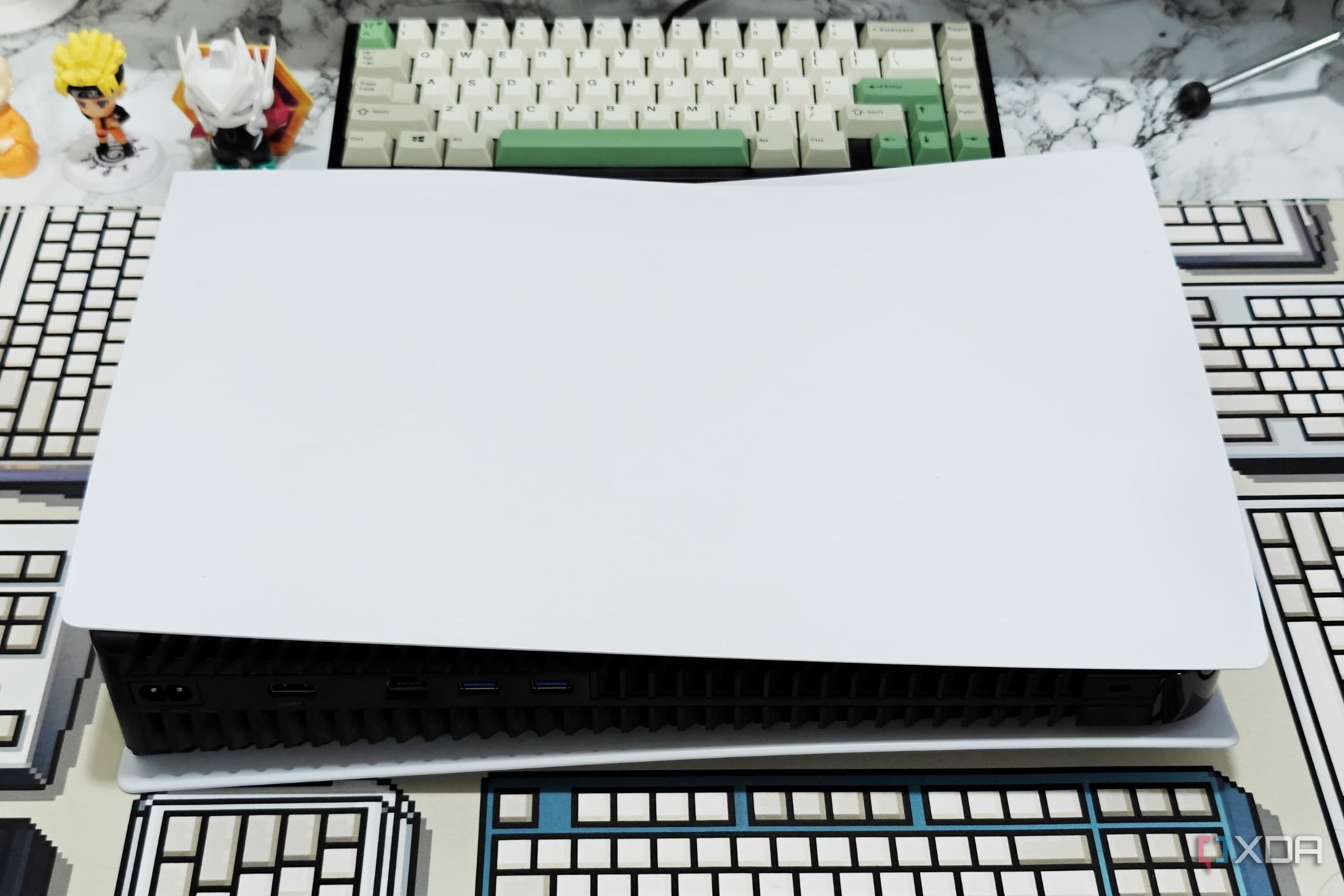 An image showing a PS5 laying flat on a table with a CRP deskmat.