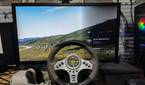 An image of a racing wheel placed near a Meta Quest 2, with Assetto Corsa running in the background