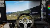 An image of a racing wheel placed near a Meta Quest 2, with Assetto Corsa running in the background