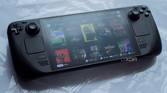 Image of Steam Deck OLED model lying on table displaying multiple games.