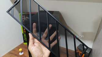 An image showing a person holding the front mesh panel with a PC case and a desk in the background.