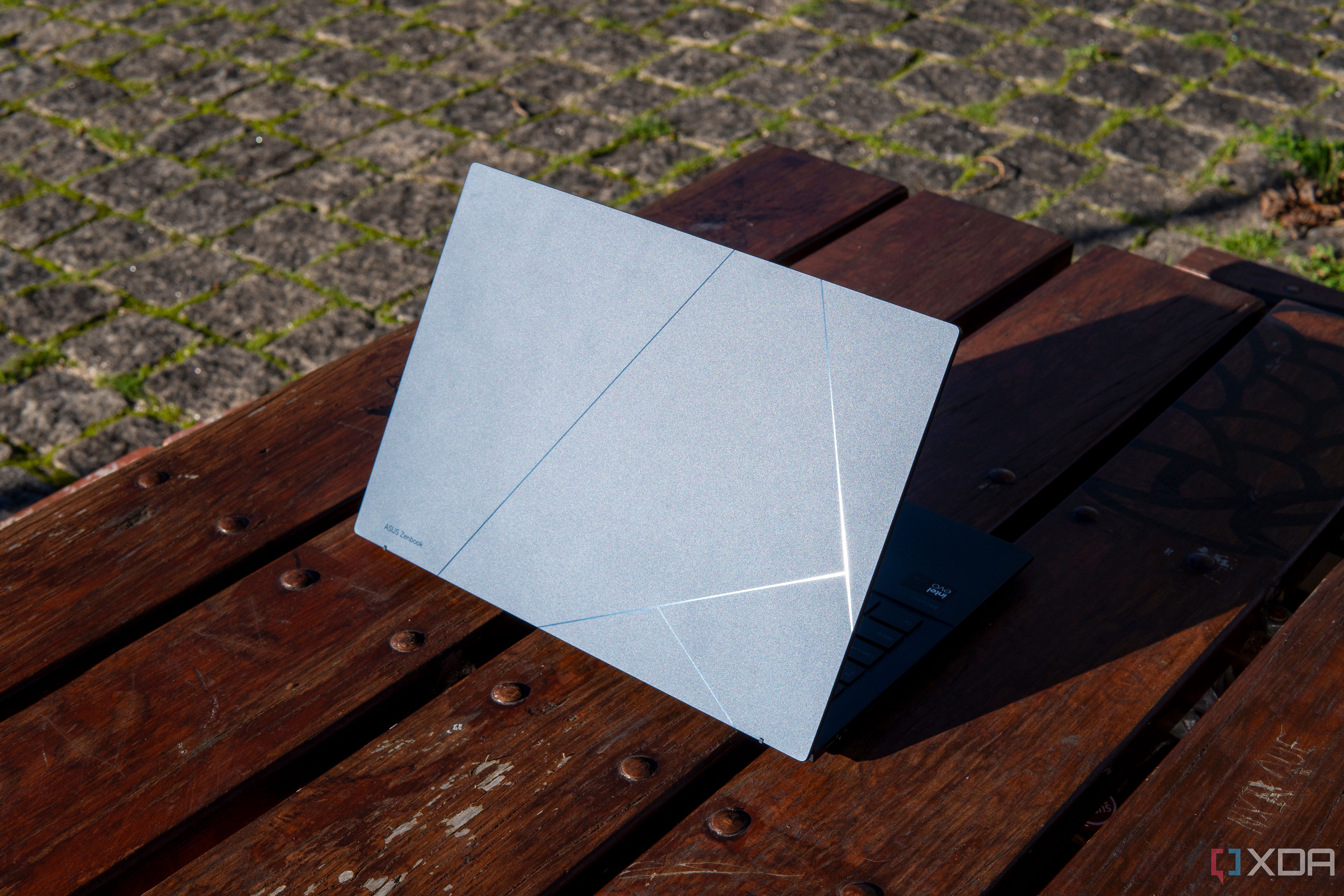Rear angled view of the Asus Zenbook 14 OLED reflecting harsh sunlight