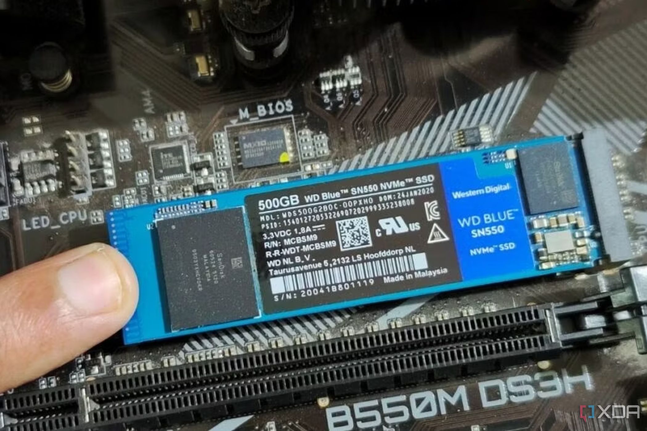 Una imagen que muestra a una persona sosteniendo un módulo SSD M.2 en su lugar con su dedo.