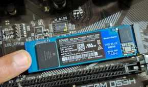 An image showing a person holding an M.2 SSD module in place with their finger.