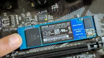 An image showing a person holding an M.2 SSD module in place with their finger.