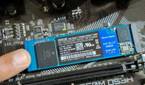 An image showing a person holding an M.2 SSD module in place with their finger.