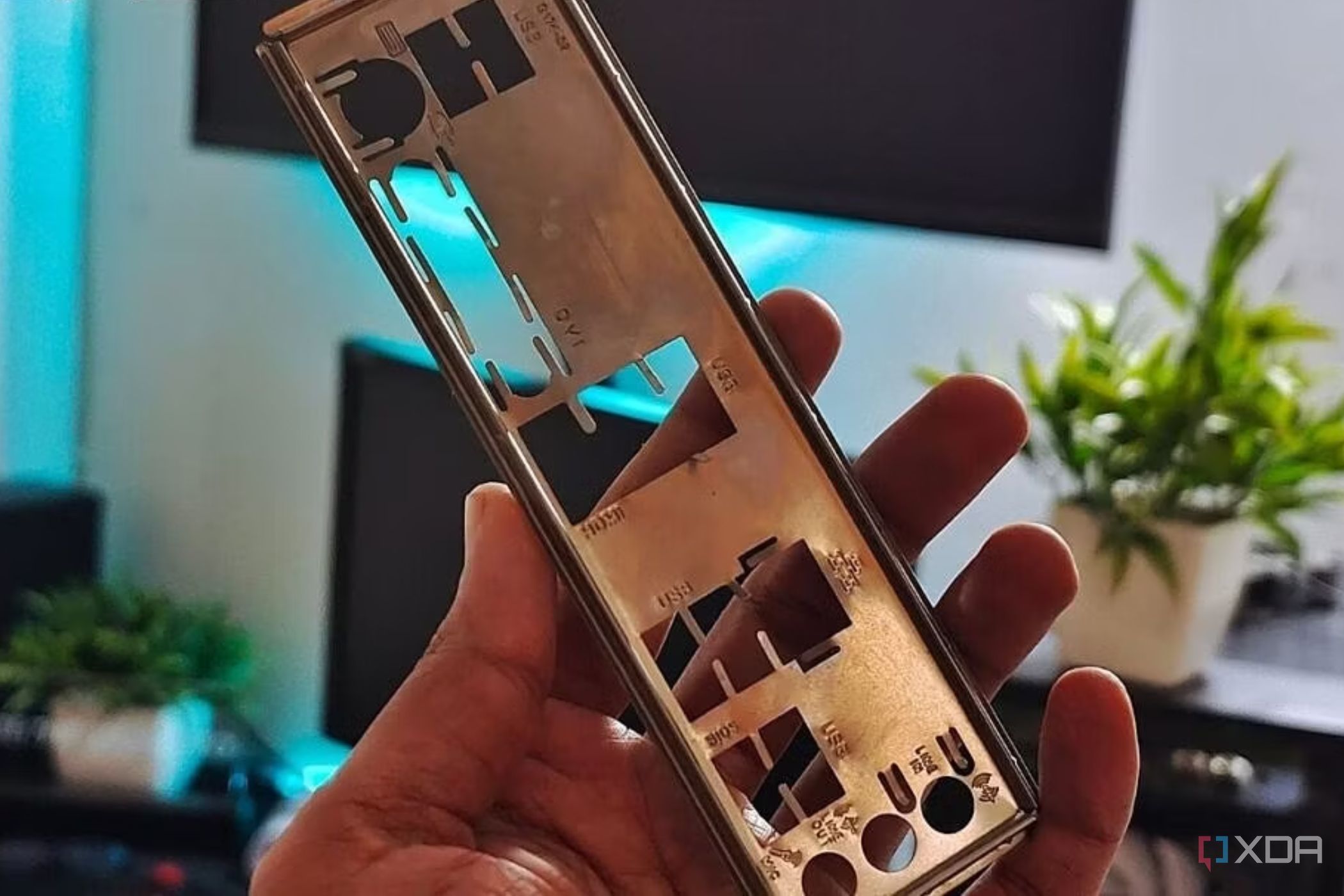 An image showing a person holding a motherboard IO plate in their hand.