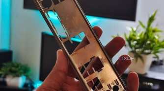 An image showing a person holding a motherboard IO plate in their hand.