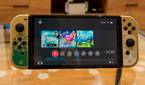 Front view of the Nintendo Switch OLED model displaying the Home menu with a game running in the background