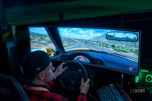 A man sitting in a gaming chair and using a steering wheel to play a videogame on a large monitor