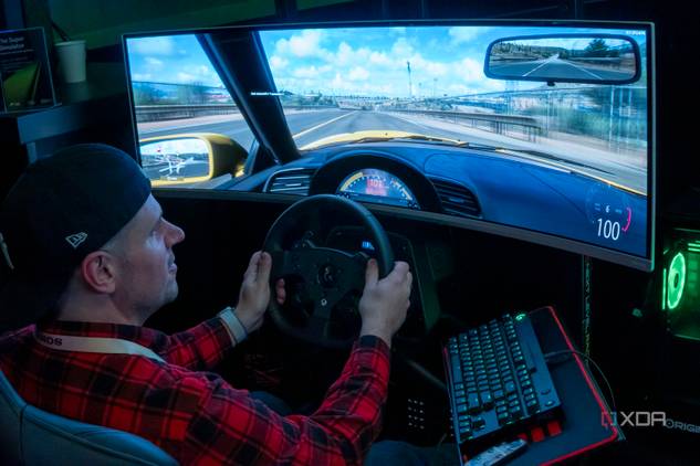 A man sitting in a gaming chair and using a steering wheel to play a videogame on a large monitor