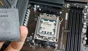 An image showing an AMD Ryzen 7 7800X3D CPU installed on a motherboard with a person in the foreground holding the socket cap in their hand.
