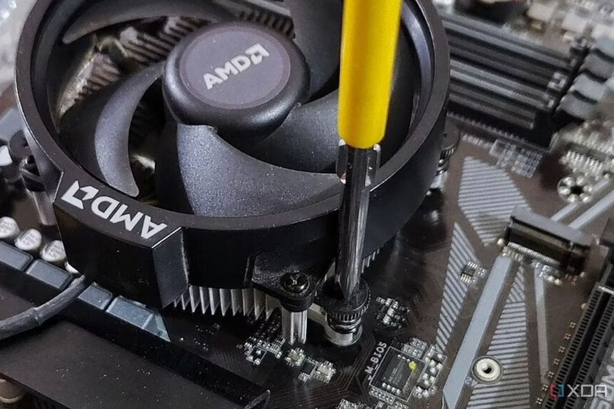 Una imagen que muestra un disipador AMD estándar atornillado a la placa base con un destornillador.