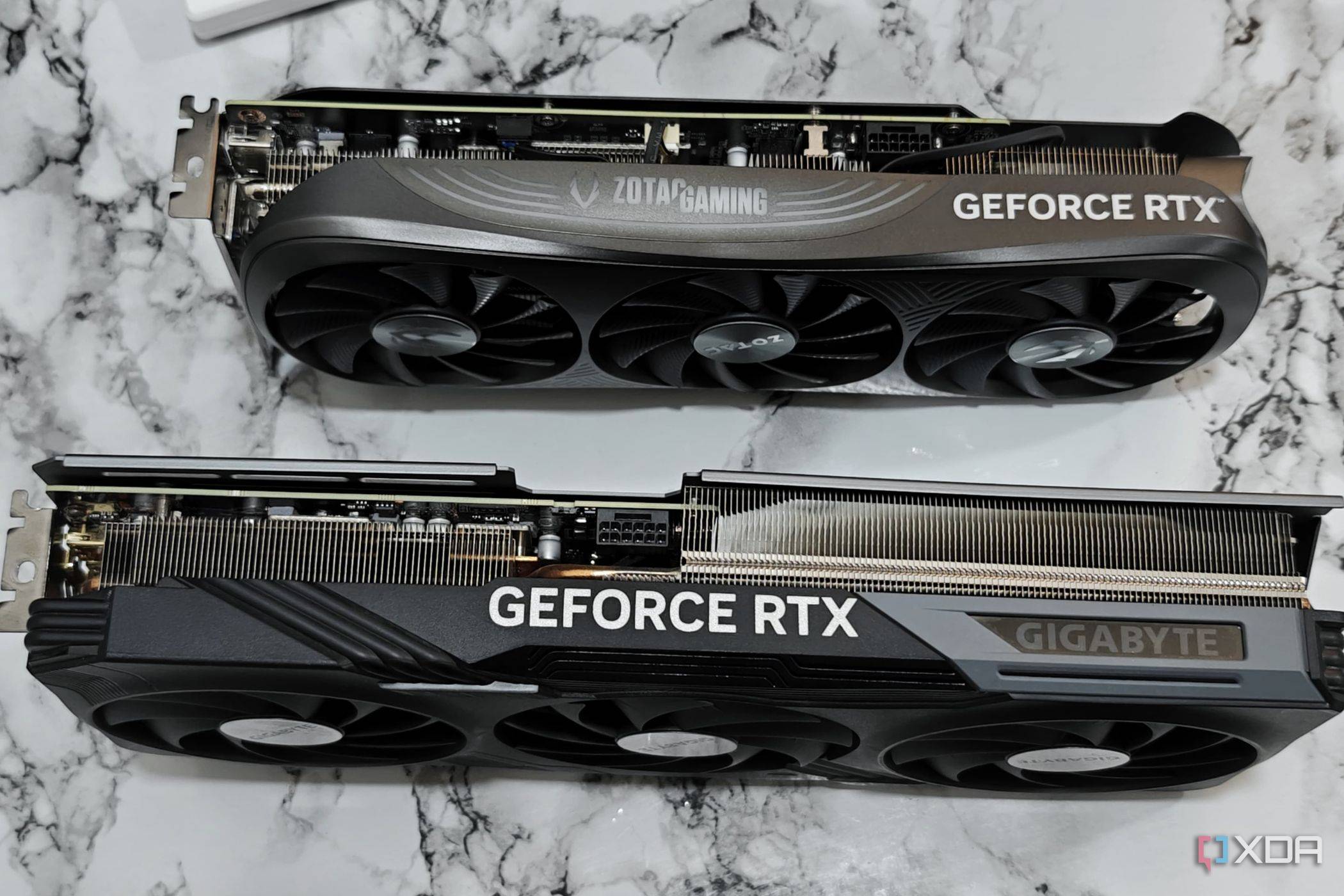 An image showing a Zotac Gaming RTX 4070 Super GPU kept next to Gigabyte RTX 4070 Ti Gaming OC GPU for size comparison.