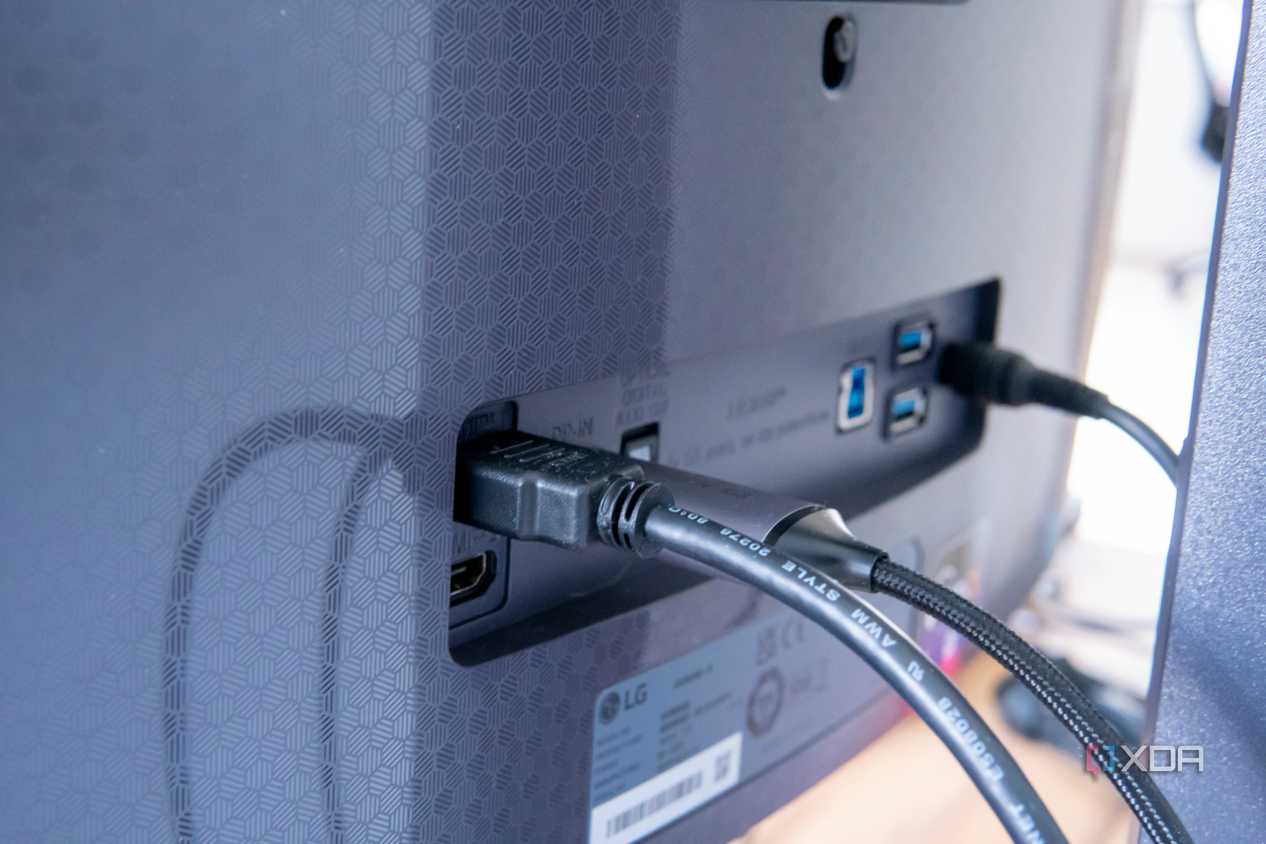 Close-up of the display inputs on the LG UltraGear 45GR95QE with HDMI and DisplayPort cables plugged in