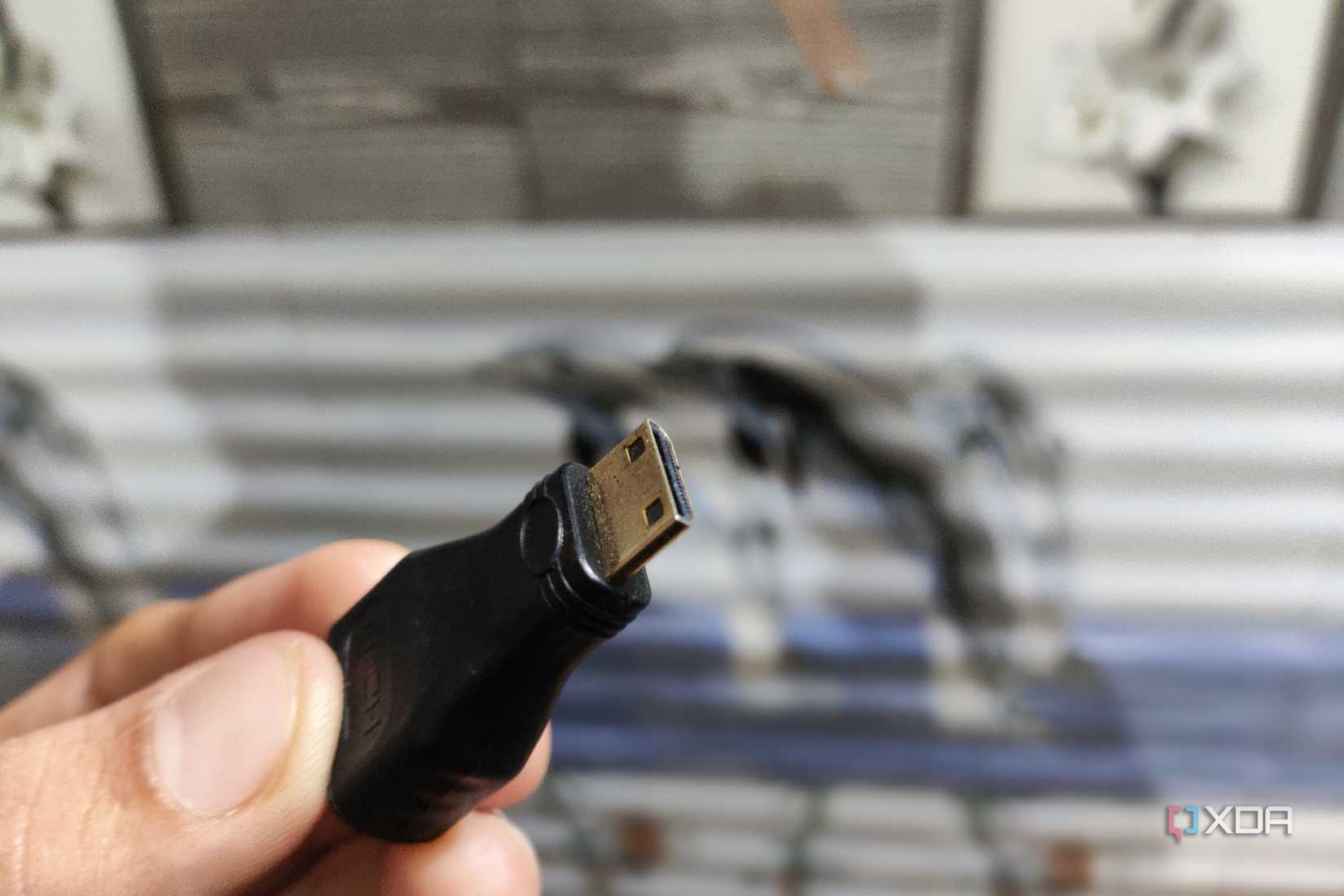 A person holding a mini HDMI to HDMI adapter