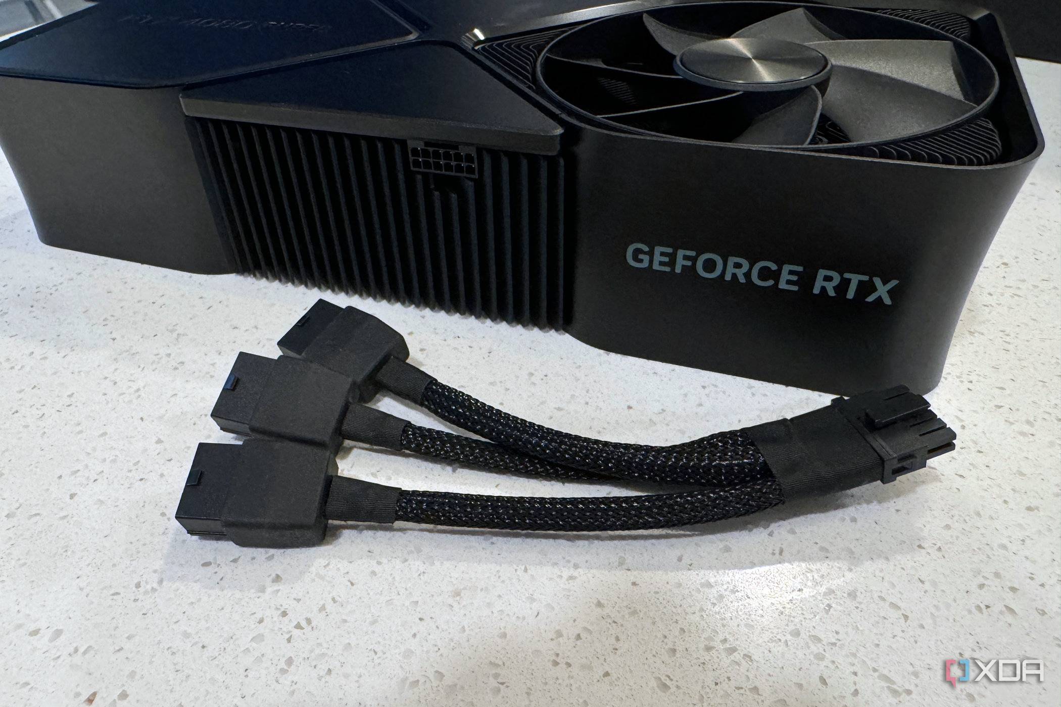 nvidia geforce rtx 4080 super fe on a table with the three cable power adapter in front of it