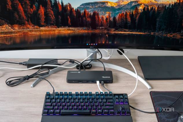 A desk setup with a monitor, keyboard, and laptop, with the Plugable TBT4-UD5 in the center