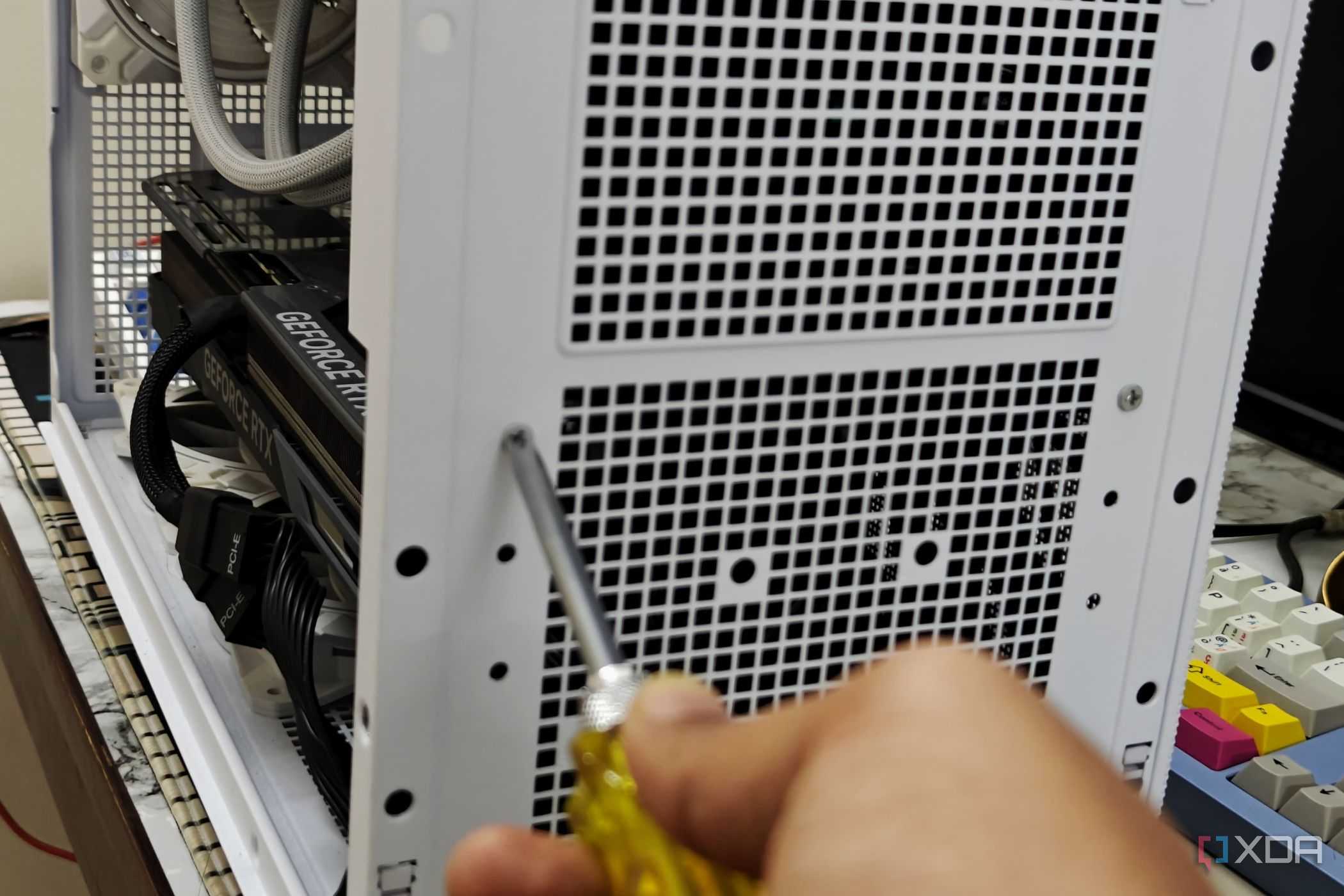 An image showing a person undoing the screws holding the PSU on the case.