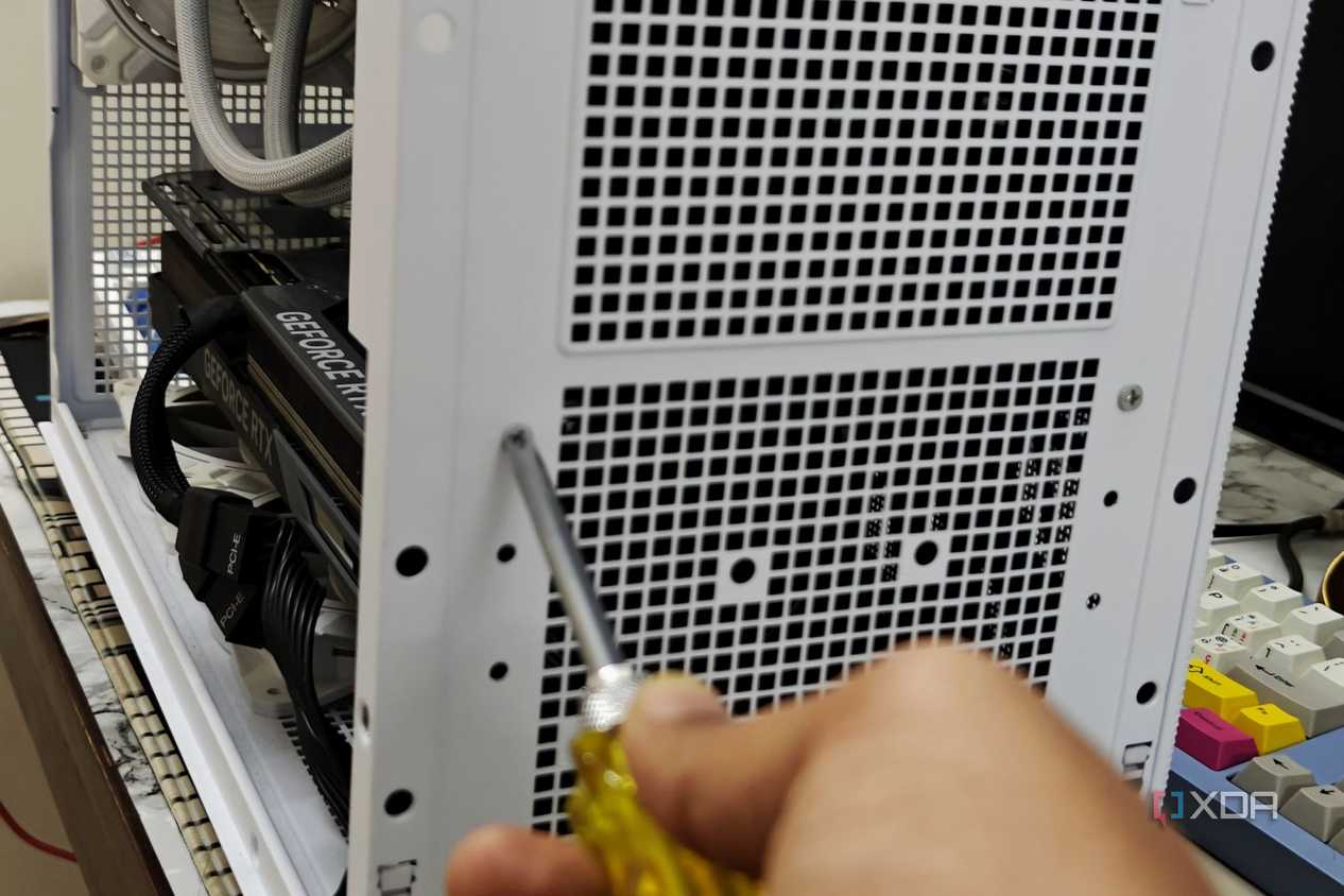An image showing a person undoing the screws holding the PSU on the case.